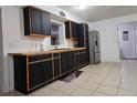 Charming kitchen featuring modern black cabinets, light wood countertops, and stainless steel appliances at 558 Tyler Ave, Deltona, FL 32725