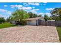 Paver driveway leads to a two-car garage, complemented by partial fencing and verdant lawn and mature trees at 704 Tangerine Ct, Winter Garden, FL 34787