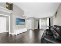 A modern living room with high ceilings, hard flooring, neutral paint, large windows, and a comfortable-looking black sofa at 10930 Buckwater Ct, Orlando, FL 32817