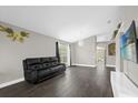Spacious living room with hardwood floors, neutral paint, a large window, and a comfortable black sofa at 10930 Buckwater Ct, Orlando, FL 32817
