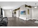 Bright living room featuring stylish shelving, hardwood floors, neutral paint, and a comfortable black sofa at 10930 Buckwater Ct, Orlando, FL 32817