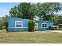 Attractive blue home with a yellow door, lush greenery, and a well-kept lawn, creating a welcoming curb appeal at 11520 Churchill St, Orlando, FL 32817