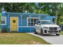Charming blue home with a bright yellow front door, complemented by lush landscaping and ample parking at 11520 Churchill St, Orlando, FL 32817