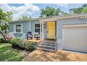 Close up front view of a cute home with a yellow door and chairs on the brick porch at 1225 Golfview St, Orlando, FL 32804