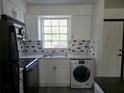Updated kitchen featuring white cabinets, black appliances, and a convenient washer-dryer unit at 1250 S Denning Dr # 108, Winter Park, FL 32789
