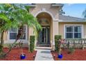 Close up of a home's entryway featuring a glass front door, potted plants, and mulch landscaping at 1913 Lazy Oaks Loop, St Cloud, FL 34771