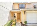 Welcoming tan two-story townhome with a front entrance, featuring a one car garage and manicured landscaping at 221 Sterling Springs Ln, Altamonte Springs, FL 32714