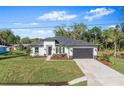 Beautifully landscaped single-story home featuring a dark gray roof, black garage door, and well-maintained lawn at 30369 Apricot Ave, Eustis, FL 32736