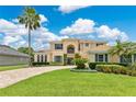 Beautiful two-story home with a well-manicured lawn, mature palm trees, and a brick driveway at 4221 Kezar Ct, Belle Isle, FL 32812