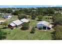 Spacious property featuring a white home with a metal roof and a detached garage, all nestled in a lush green landscape at 4895 Cr 134B, Wildwood, FL 34785