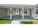 Covered porch with white pillars, grey painted floor and white door with decorative window at 5160 Wood Ridge Ct, Ocoee, FL 34761