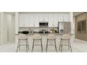 Modern kitchen with white cabinets, stainless steel appliances, and an island with seating at 809 Tundra Loop, Groveland, FL 34736