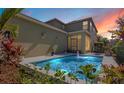 Sparkling pool with illuminated water features is surrounded by colorful landscaping and a cozy patio area at 8256 Bayview Crossing Dr, Winter Garden, FL 34787