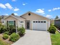 Charming single-story home featuring an attached garage, well-maintained lawn, and mature landscaping at 6231 Atkinson Ln, The Villages, FL 32163