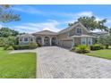 Beautiful home exterior featuring a lush green lawn, mature trees, and a paver driveway at 1017 Parkside Pointe Blvd, Apopka, FL 32712