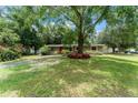 Charming front exterior featuring mature trees, green lawn, and an inviting red door at 17 S Aurora Dr, Apopka, FL 32703