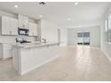 Open-concept kitchen with white cabinets, island, and adjacent living area with sliding glass doors at 2502 Linda Knoll Ln, Bartow, FL 33830