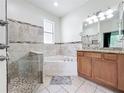 Bright bathroom with a soaking tub, glass enclosed shower, and a granite countertop vanity at 2528 Double Tree Pl, Oviedo, FL 32766