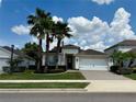 Charming home featuring an attached two-car garage, manicured landscaping, and mature palm trees at 541 Kistler Cir, Clermont, FL 34715