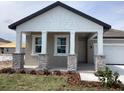 Inviting front porch with stone pillar accents and white columns, exuding curb appeal at 5733 Haystack Drive, St Cloud, FL 34771