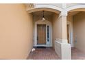 Inviting front entrance with brick pathway, decorative light fixture, and classic brown door under an arched entryway at 6360 Ranelagh Dr # 104, Orlando, FL 32835