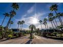 Palm tree lined entrance to the community with brick paved road and metal gates under a sunny sky at 3010 Egrets Landing Dr, Lake Mary, FL 32746