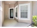 Cozy entryway with a black door, a window with white trim and tan stucco siding at 1062 Wickerwood St, Ocoee, FL 34761