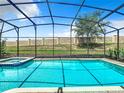 An inviting screened-in pool and spa, complete with a decorative privacy wall at 1478 Moon Valley Dr, Davenport, FL 33896
