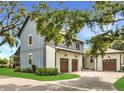Side view of home with blue and white siding, brick driveway, and two car garage with dark wood doors at 15198 E Oakland Ave, Winter Garden, FL 34787