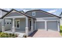 Inviting home featuring light blue exterior, a two-car garage, and covered front porch with stone columns and brick-paved driveway at 16489 Silver Brook Way, Winter Garden, FL 34787