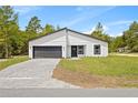 Modern home boasts a gray brick driveway, complemented by a black garage door and a clean, minimalist white exterior at 17762 Sw 33Rd Ter, Ocala, FL 34473