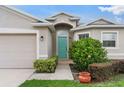 Inviting entryway with a turquoise-colored door, lush landscaping, and a cozy walkway at 1805 Kingsmill Dr, Bartow, FL 33830