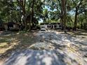 Wide shot of the front of the home, which has a large parking area and green trees at 25824 Shawnee St, Sorrento, FL 32776