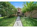Inviting home featuring a stone pathway, lush greenery, and a charming entryway at 453 Sorrento Rd, Kissimmee, FL 34759