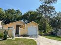 A single-story yellow house with a one car garage and gated front courtyard on a sunny day at 561 Portland Cir, Apopka, FL 32703
