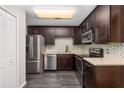 Bright kitchen with stainless steel appliances, mosaic tile backsplash, dark cabinetry and modern fixtures at 6245 Sleepy Hollow Dr, Orlando, FL 32810