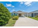 Inviting single-story home with a covered carport, enhanced by verdant landscaping and a well-kept lawn at 747 Louise Ln, The Villages, FL 32163