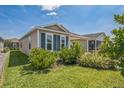 Close up showing the charming single-story home featuring lush landscaping and neutral siding with blue shutters at 747 Louise Ln, The Villages, FL 32163