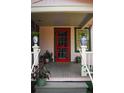 Close-up of the covered front porch of a pink cottage with a red door and potted plants at 748 W Florence Ave, Deland, FL 32720
