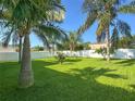 Expansive backyard featuring a lush lawn, mature palm trees, and a white privacy fence at 1208 Castleport Rd, Winter Garden, FL 34787