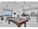 Open-concept living area featuring a pool table, white sofa, and modern kitchen with bar seating at 150 E Robinson St # 2111, Orlando, FL 32801