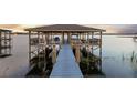 Covered boat dock on the water, with boat lift, seating area, and walkway at 16086 Johns Lake Overlook Dr, Winter Garden, FL 34787