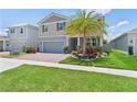 Attractive two-story home featuring a brick driveway, two-car garage, lush lawn and palm tree at 2227 Blue Salvia St, Clermont, FL 34711
