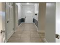 Bright hallway featuring tile flooring and white trim, leading to a front door with decorative glass at 2318 Mohawk Trl, Maitland, FL 32751