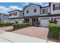 Inviting townhome exterior with a brick paver driveway, trimmed hedges, and attached garage at 328 Cedar Bark Ln, Sanford, FL 32771