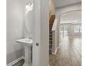 Hallway view with wood-look tile, staircase, half bathroom with pedestal sink, and view to living area at 328 Cedar Bark Ln, Sanford, FL 32771