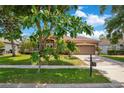 Inviting single-story home featuring a well-kept lawn, lush landscaping, and a convenient two-car garage at 4047 Lillian Hall Ln, Orlando, FL 32812