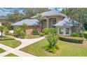 Exterior of a tan home showing the yard with green grass, driveway, and manicured bushes at 4052 Gilder Rose Pl, Winter Park, FL 32792