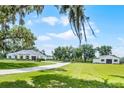 Idyllic property featuring a long driveway, and additional building, complemented by well-manicured lawns and mature shade trees at 5478 Nw 153Rd Ct, Morriston, FL 32668
