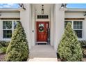 Inviting front entrance with a red door, complemented by stylish lighting fixtures and manicured greenery at 5478 Nw 153Rd Ct, Morriston, FL 32668